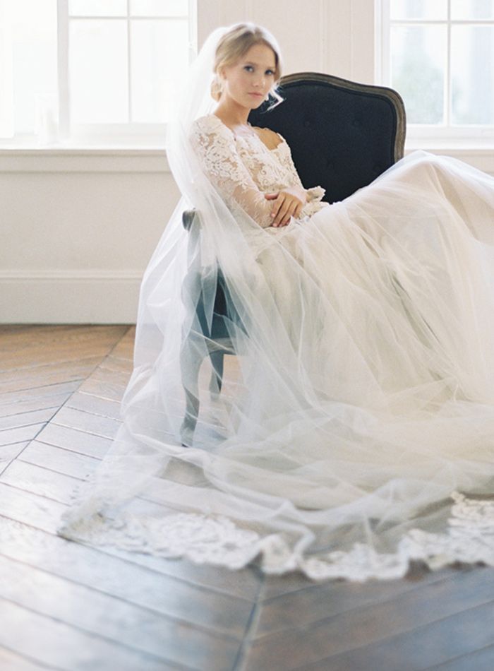 A bride in a wedding dress and veil is sitting in a chair.