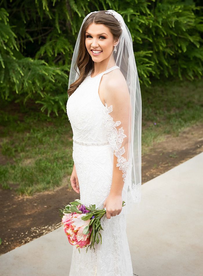 The bride is wearing a veil and holding a bouquet of flowers.