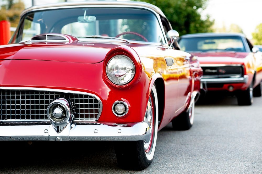 Red vintage car on a street with another classic car behind it