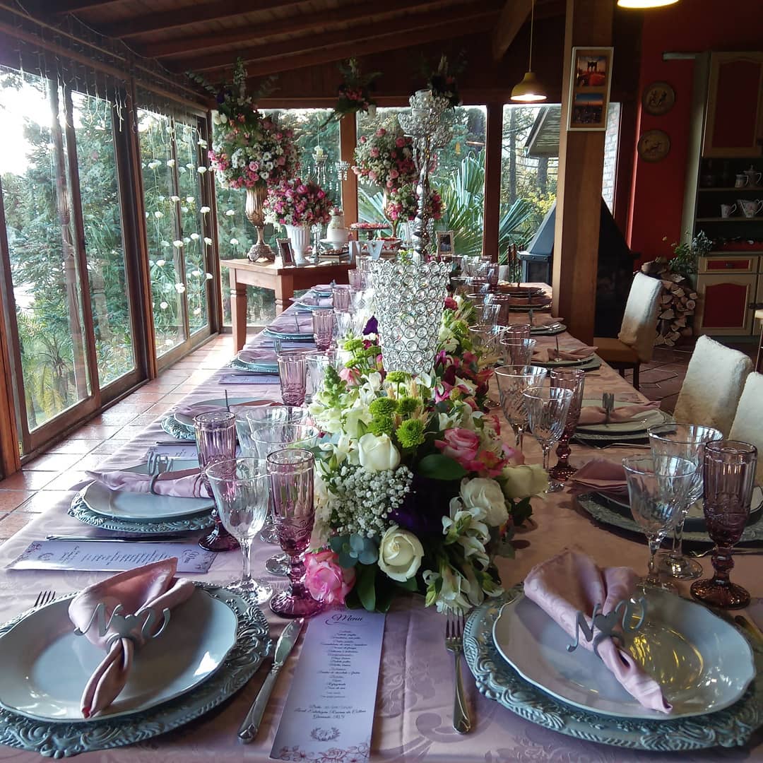 Uma longa mesa com pratos, copos e flores.