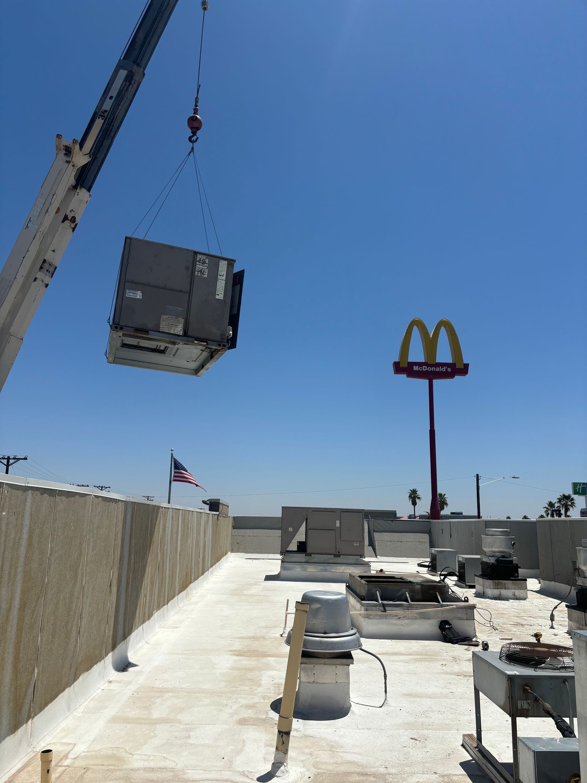 A crane is lifting a mcdonald 's sign on top of a building