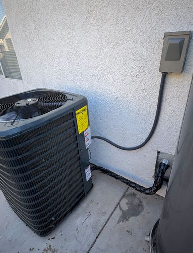 An air conditioner is sitting on the sidewalk next to a wall.