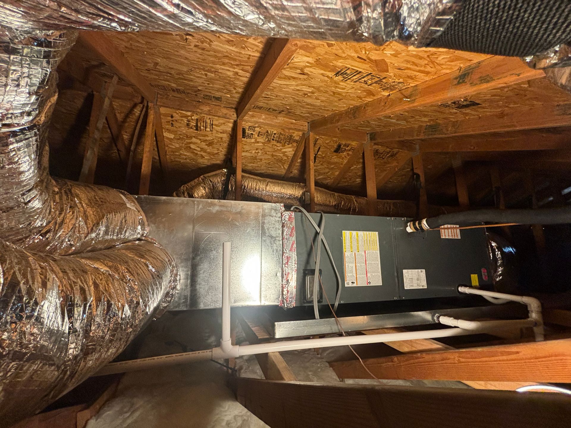 A picture of an air conditioner in the attic of a house.