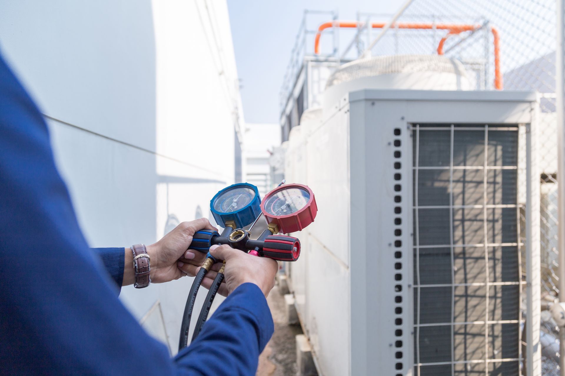 A man is working on an air conditioner outside of a building.
