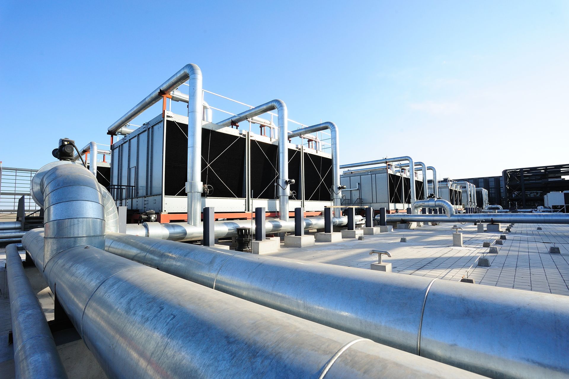 A row of pipes are lined up on a rooftop with a blue sky in the background.