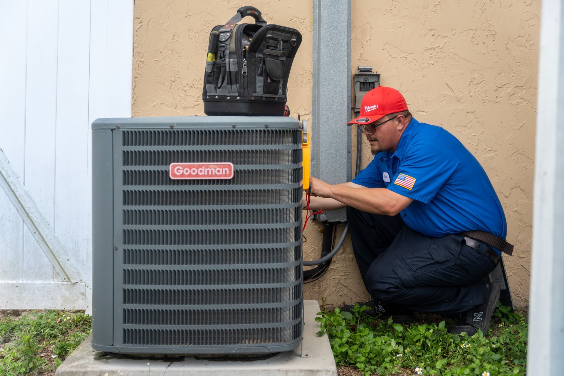 A man is working on an air conditioner outside of a house.