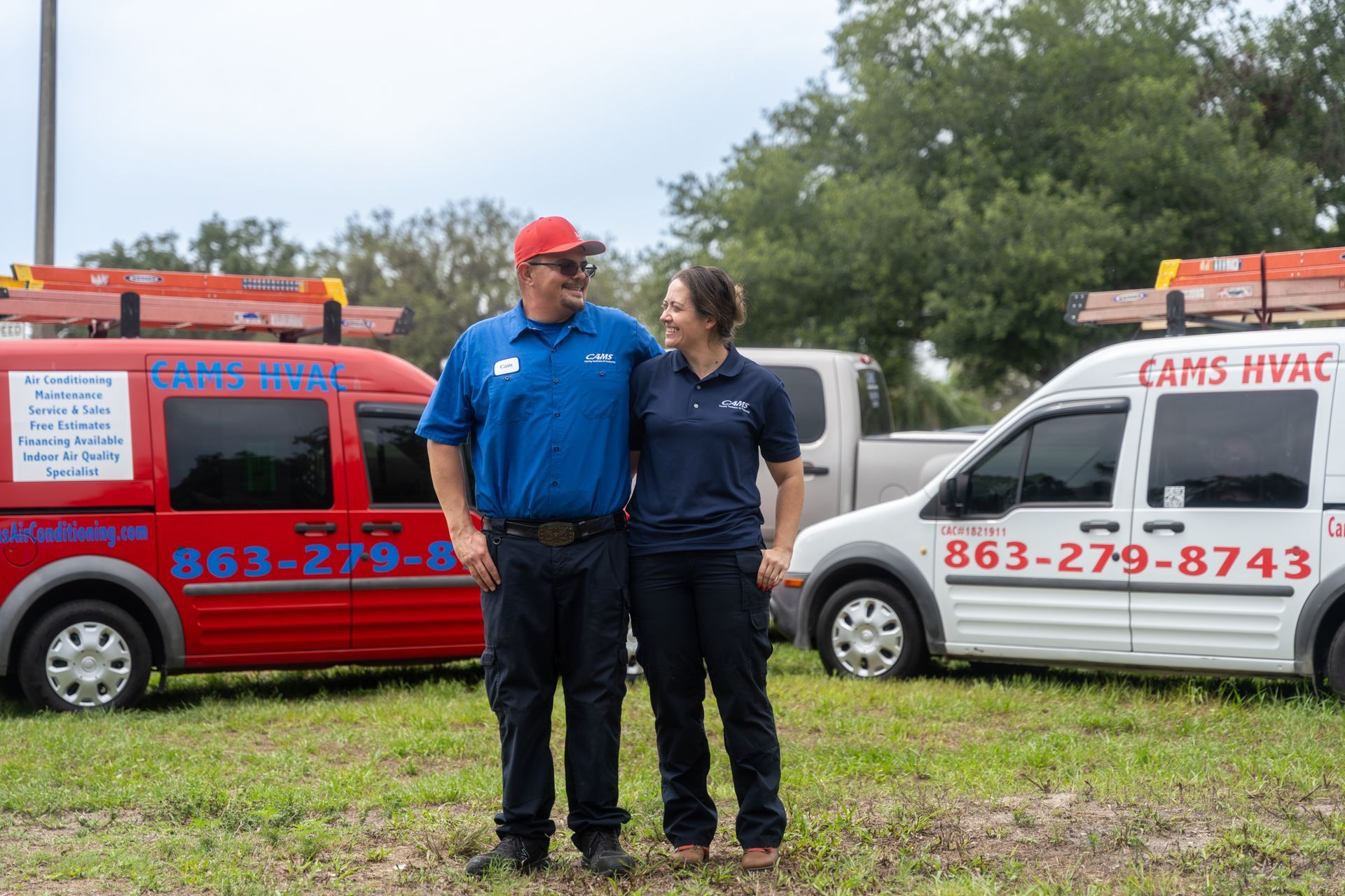 A man and a woman are standing in front of two vans.