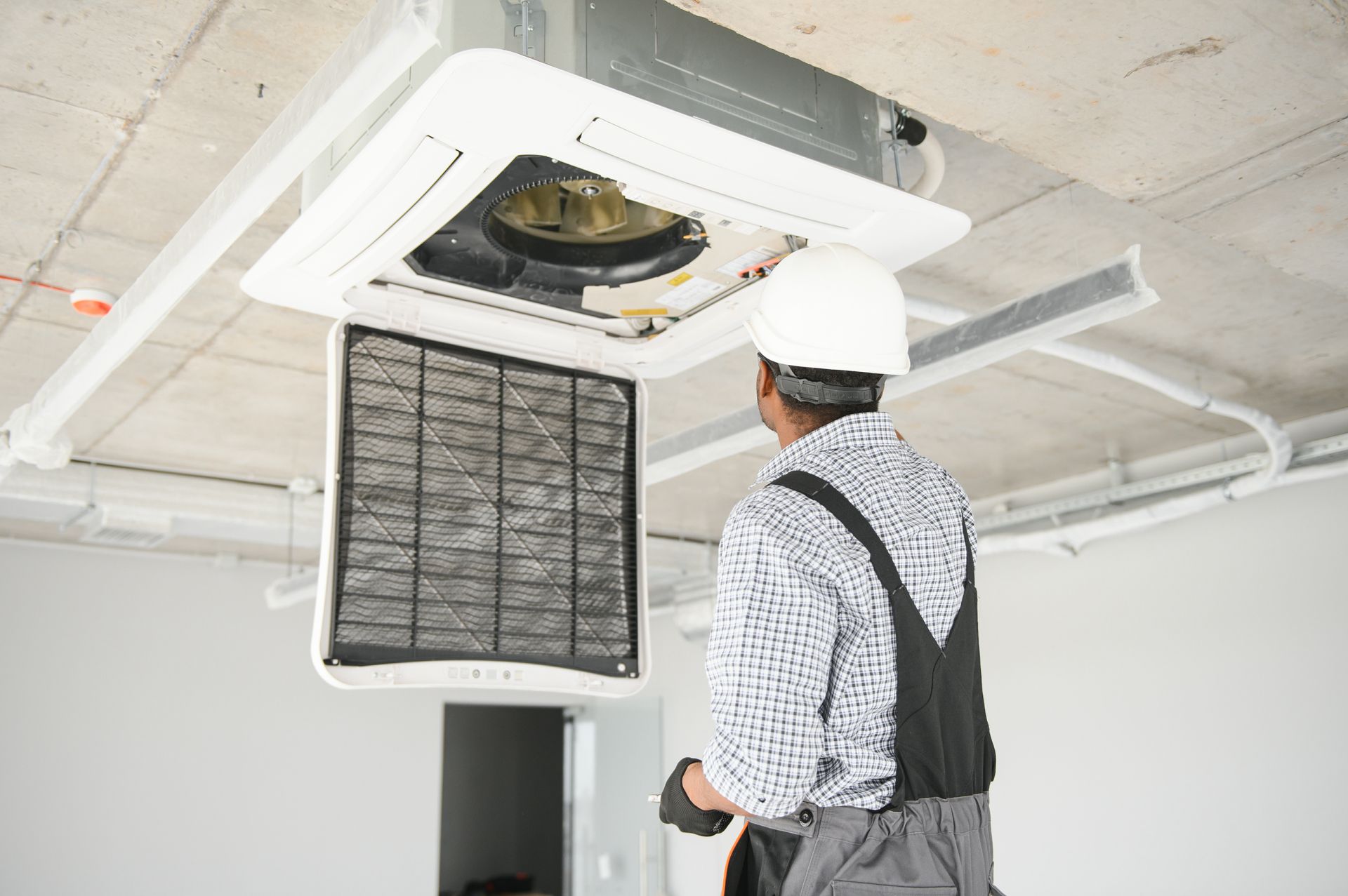 A man is working on an air conditioner in a building.