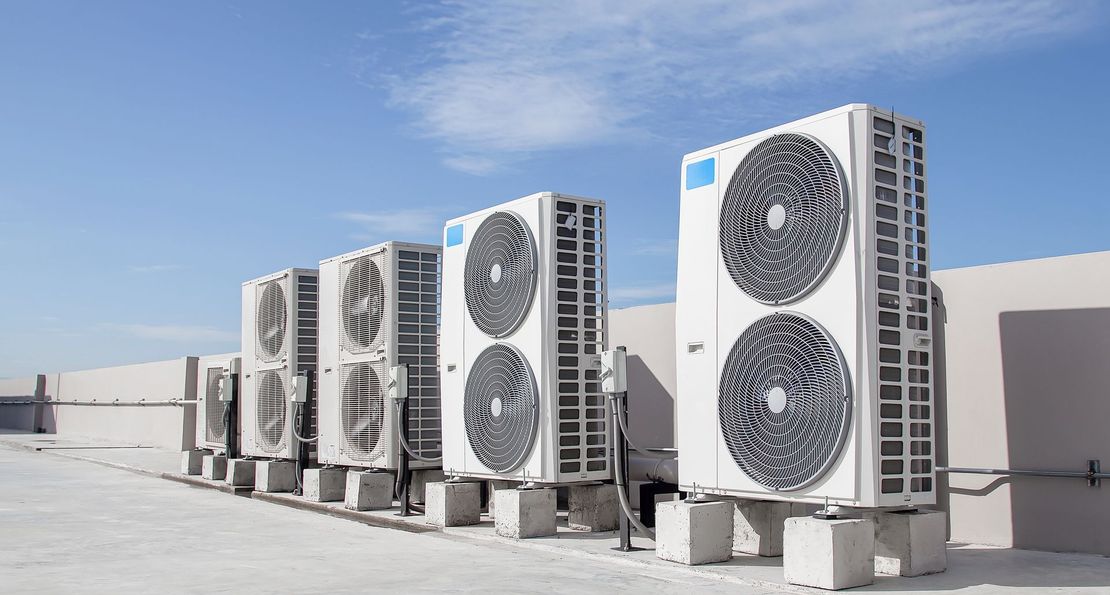 A row of air conditioners are sitting on top of a building.