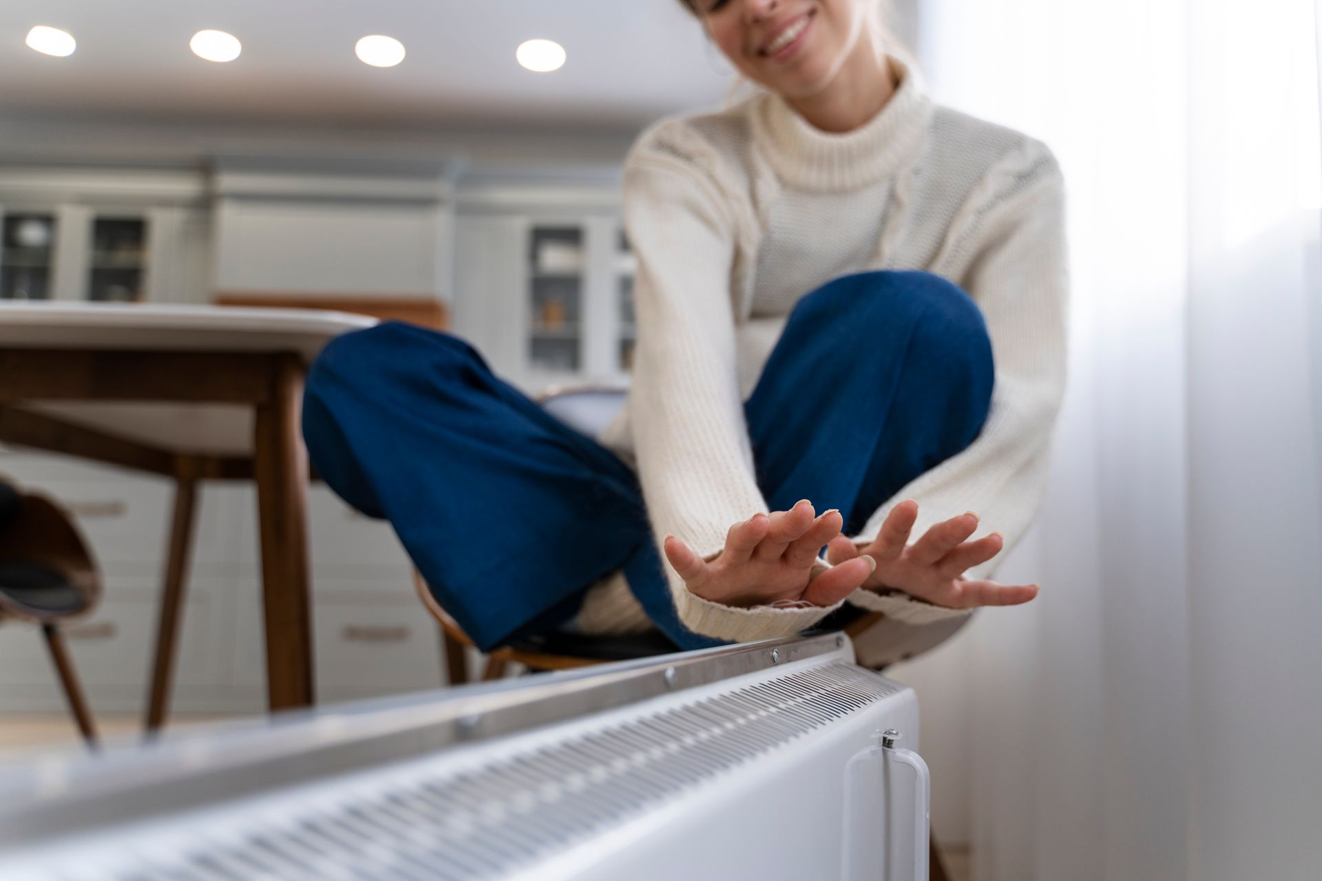 A woman is sitting on the floor next to a radiator.