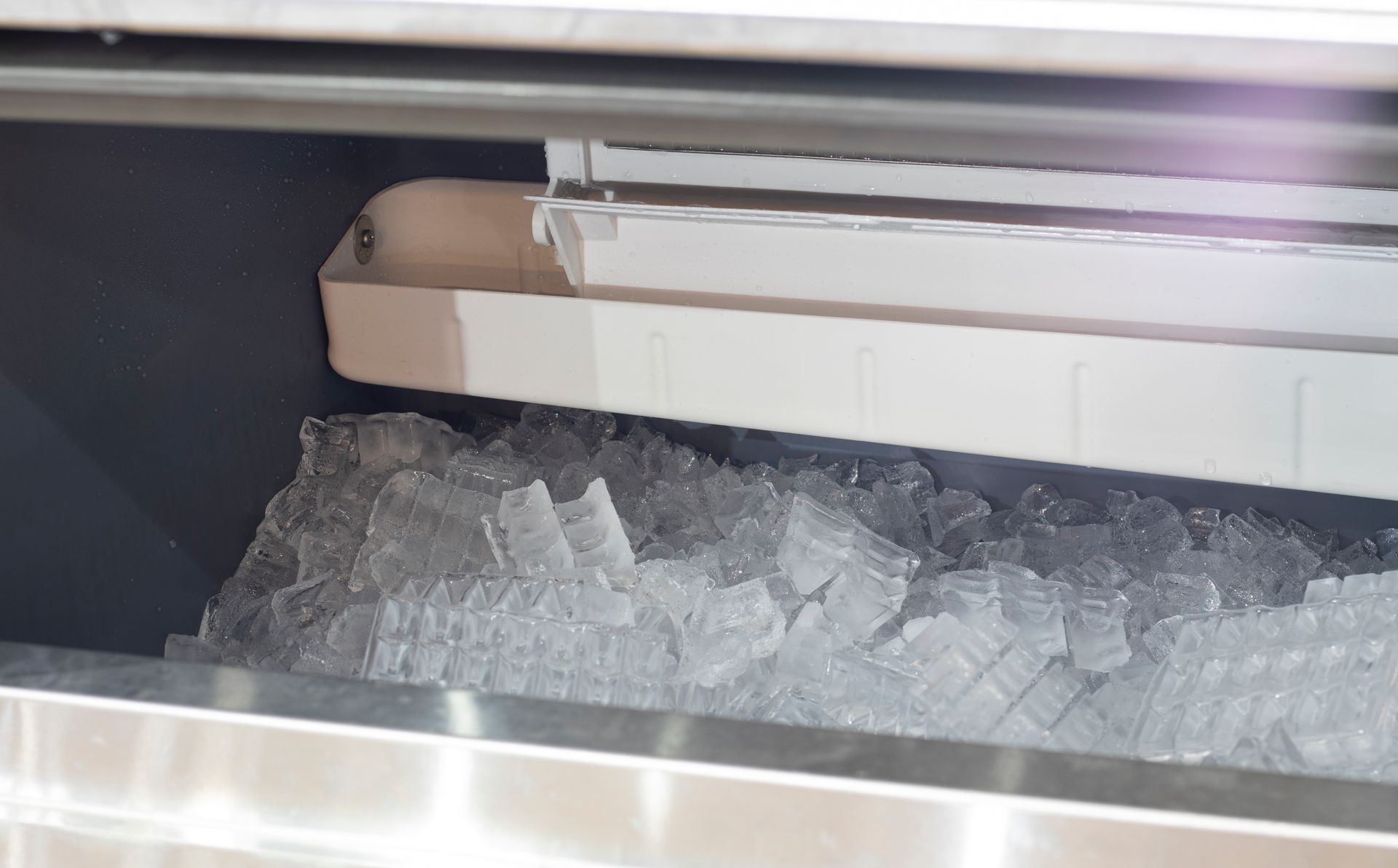 A tray of ice cubes in a stainless steel ice maker