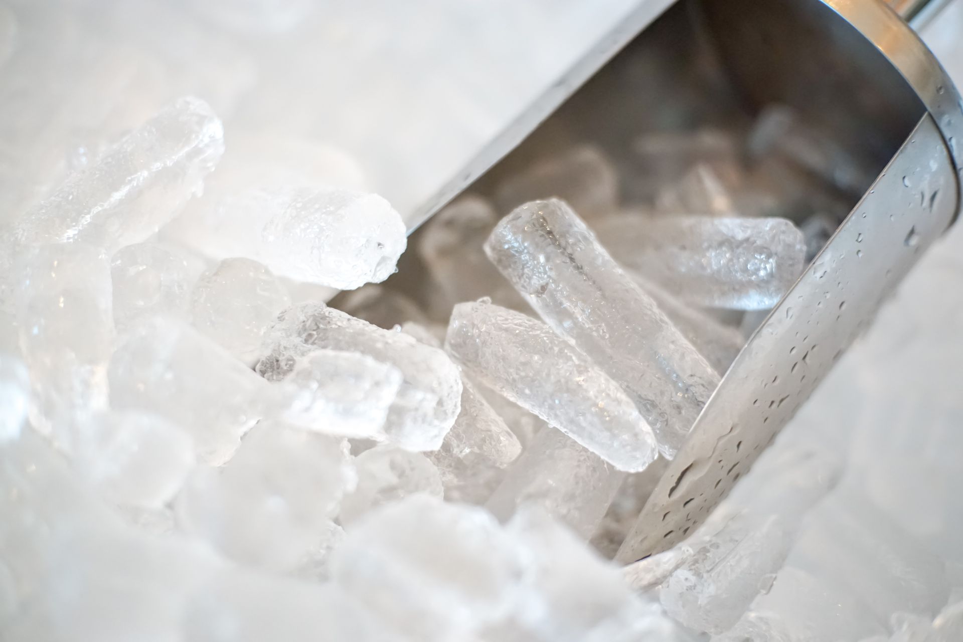 A scoop of ice is sitting on top of a pile of ice cubes.