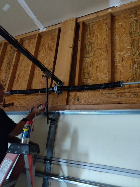 Person adjusting garage door opener on exposed wooden wall frame