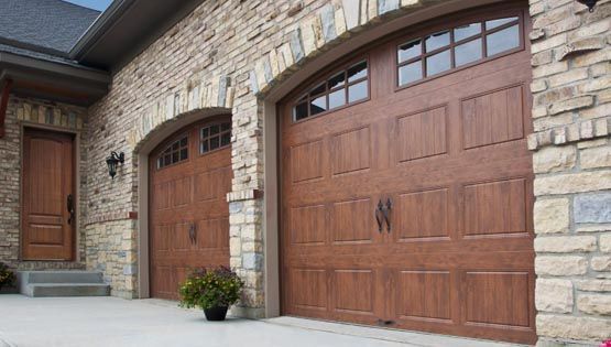 Stone house exterior with two wooden garage doors and a front entry door