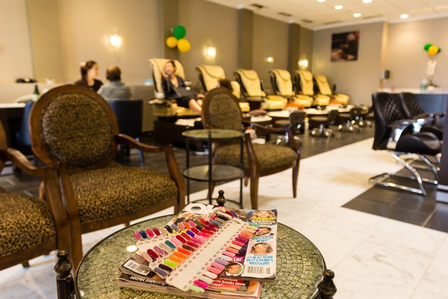 Nail salon interior with chairs, nail polish swatches, and clients receiving pedicures.