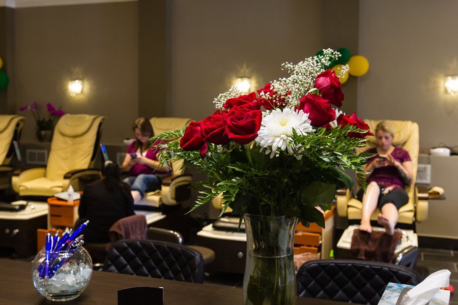 Nail salon interior: bouquet of red roses, women getting pedicures in massage chairs.