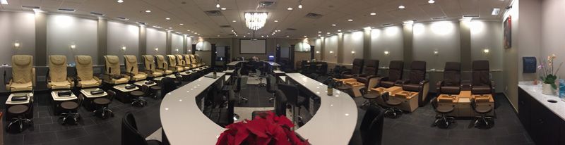 A nail salon interior with rows of pedicure chairs, a curved counter, and a projection screen.