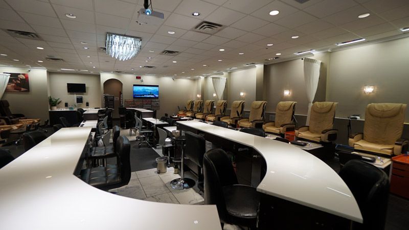 Interior of a nail salon with chairs, tables, and a television.