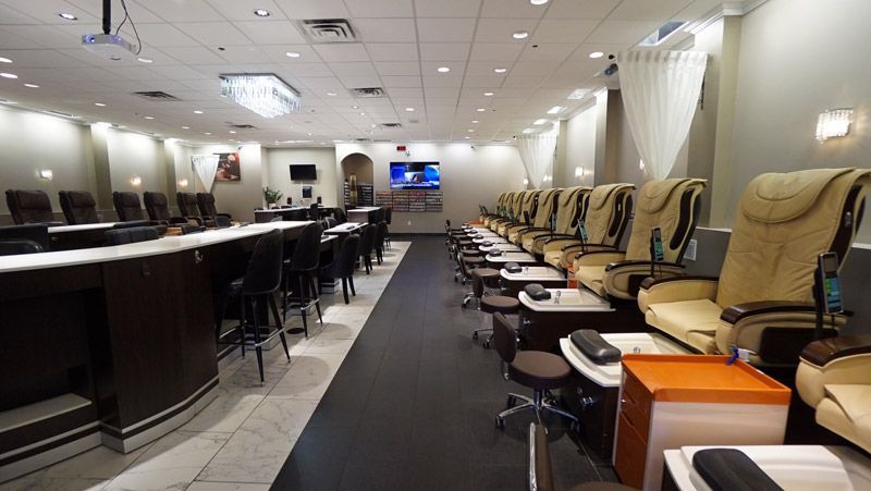 Nail salon interior with pedicure chairs, manicure bar, and a TV.