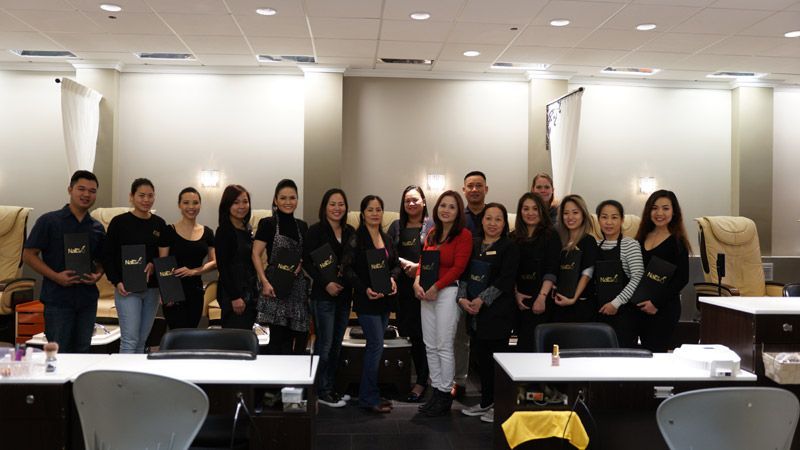 Group of nail technicians posing together in a salon.