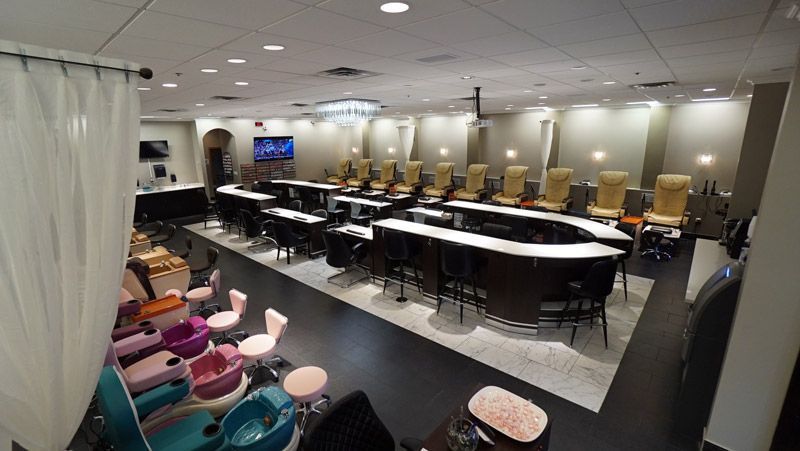 A nail salon interior with rows of manicure stations and pedicure chairs.