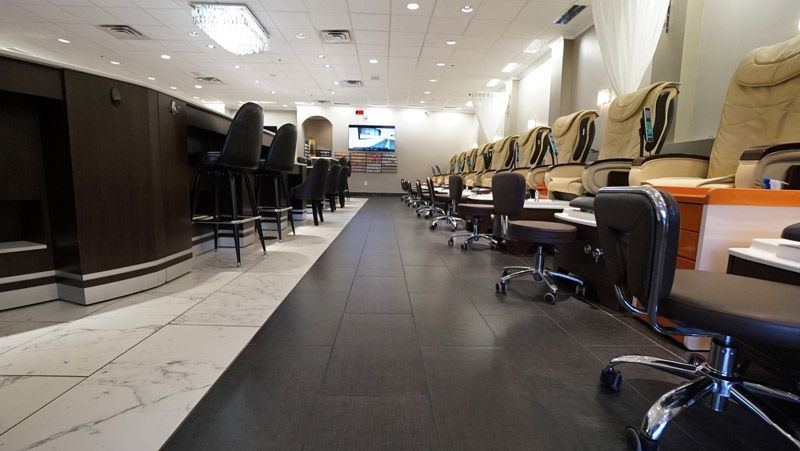 Interior of a nail salon with manicure stations, pedicure chairs, and a bar area.
