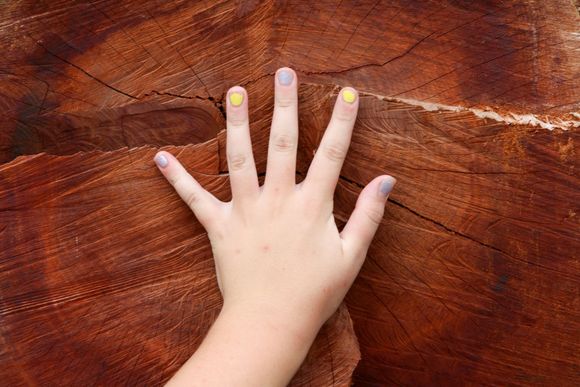 Girl in bathrobe applies nail polish, red lipstick smeared on face.
