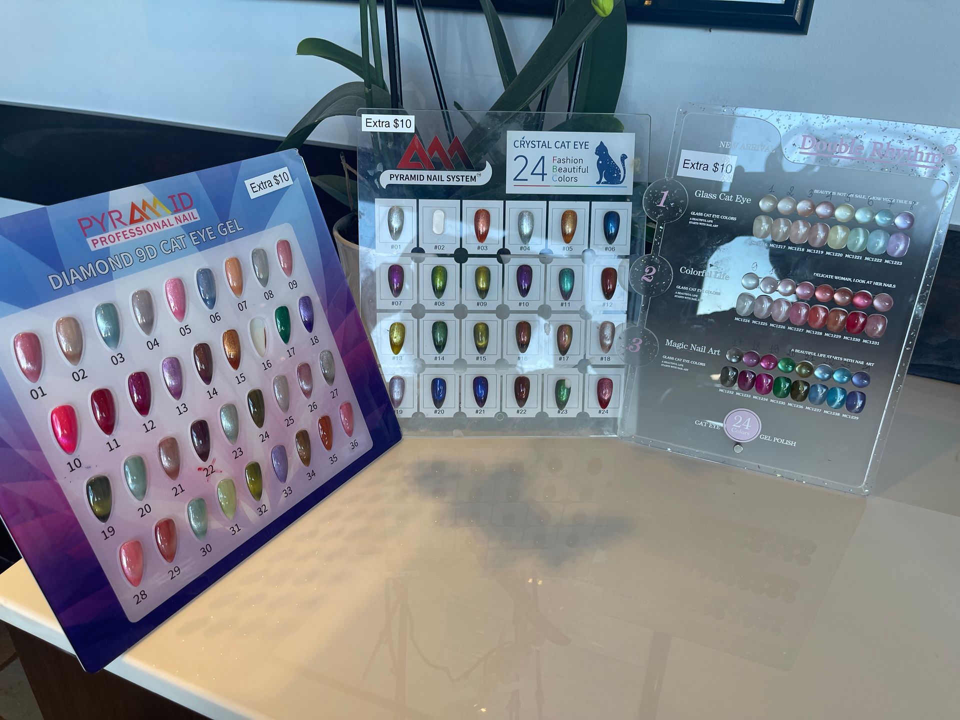 Nail polish color swatches displayed on a table in three clear plastic holders, showcasing a variety of shades.