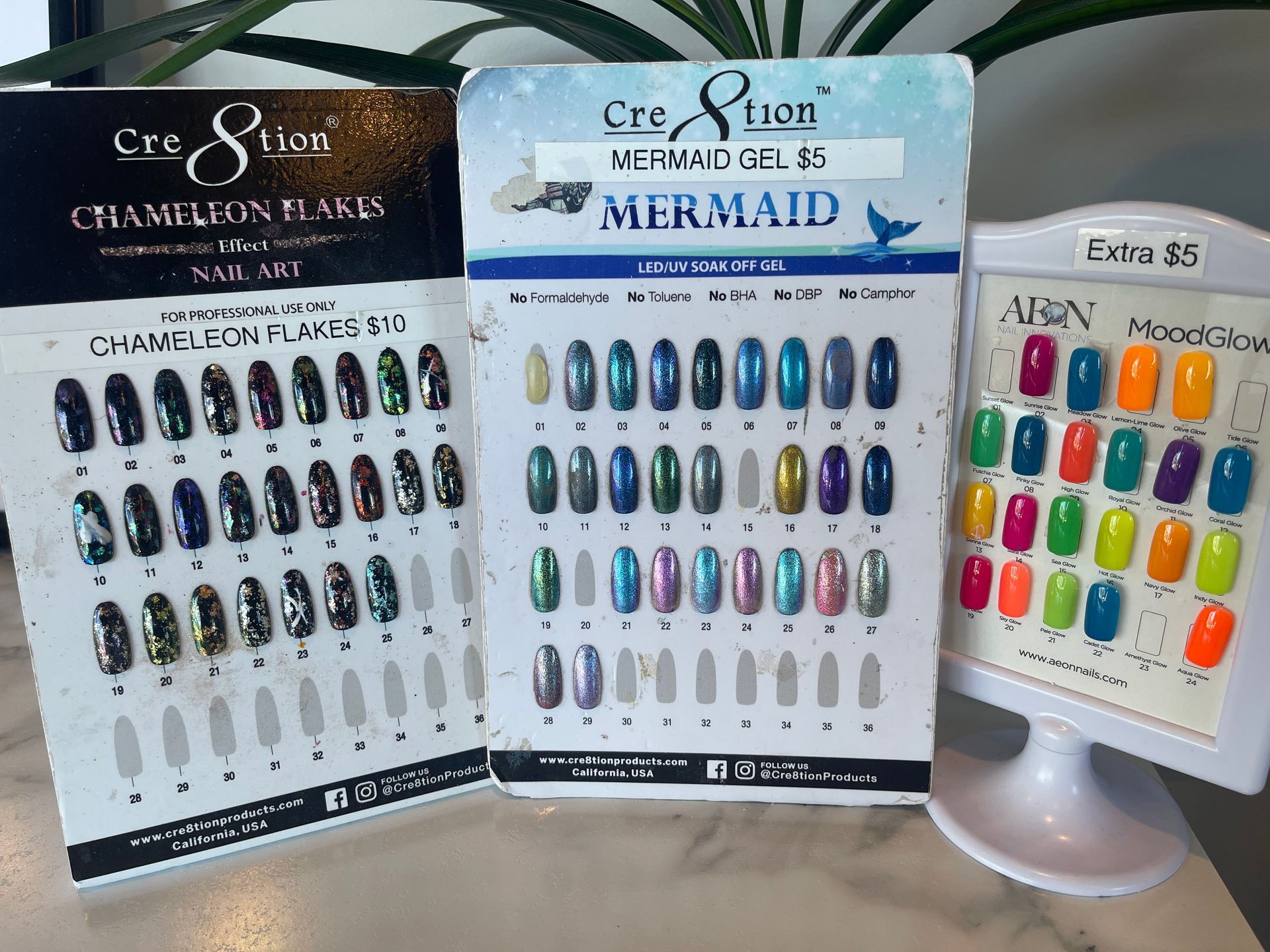 Nail polish color samples displayed on cards, featuring various shades and finishes, including mermaid and chameleon effects.