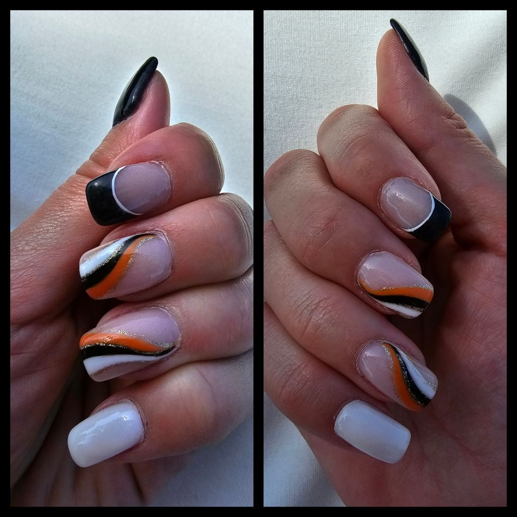 Hands with gel nail designs: black, white, orange curved stripes and black French tips.