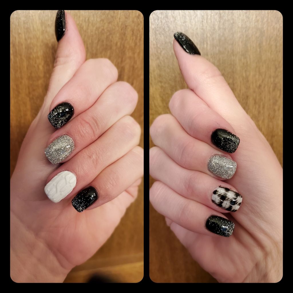 Two hands with black, silver, and white nail designs, including glitter and checkered patterns.