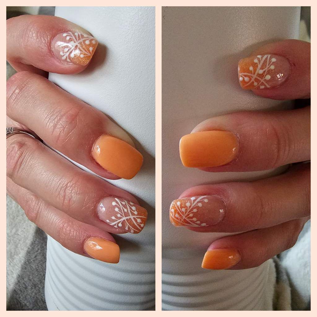 Two hands with orange nail polish, one with white snowflake designs, holding a white mug.
