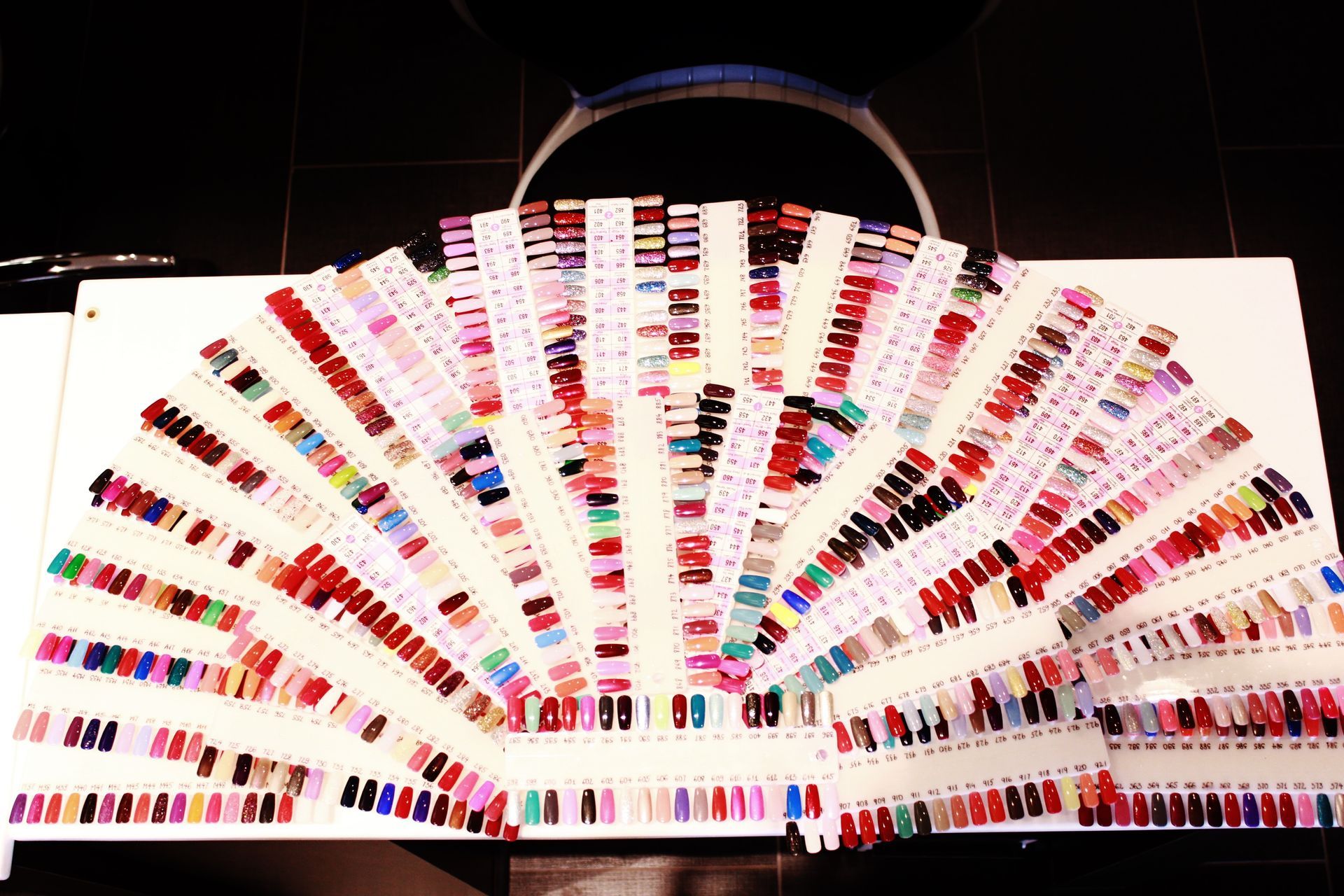 Hands soaking in a wooden bowl with a daisy; French manicured nails, blue accents.
