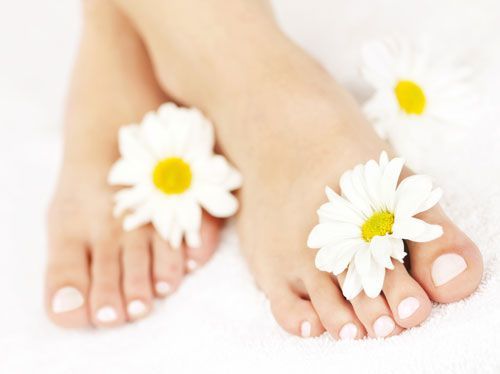 Feet with white nail polish and daisies.