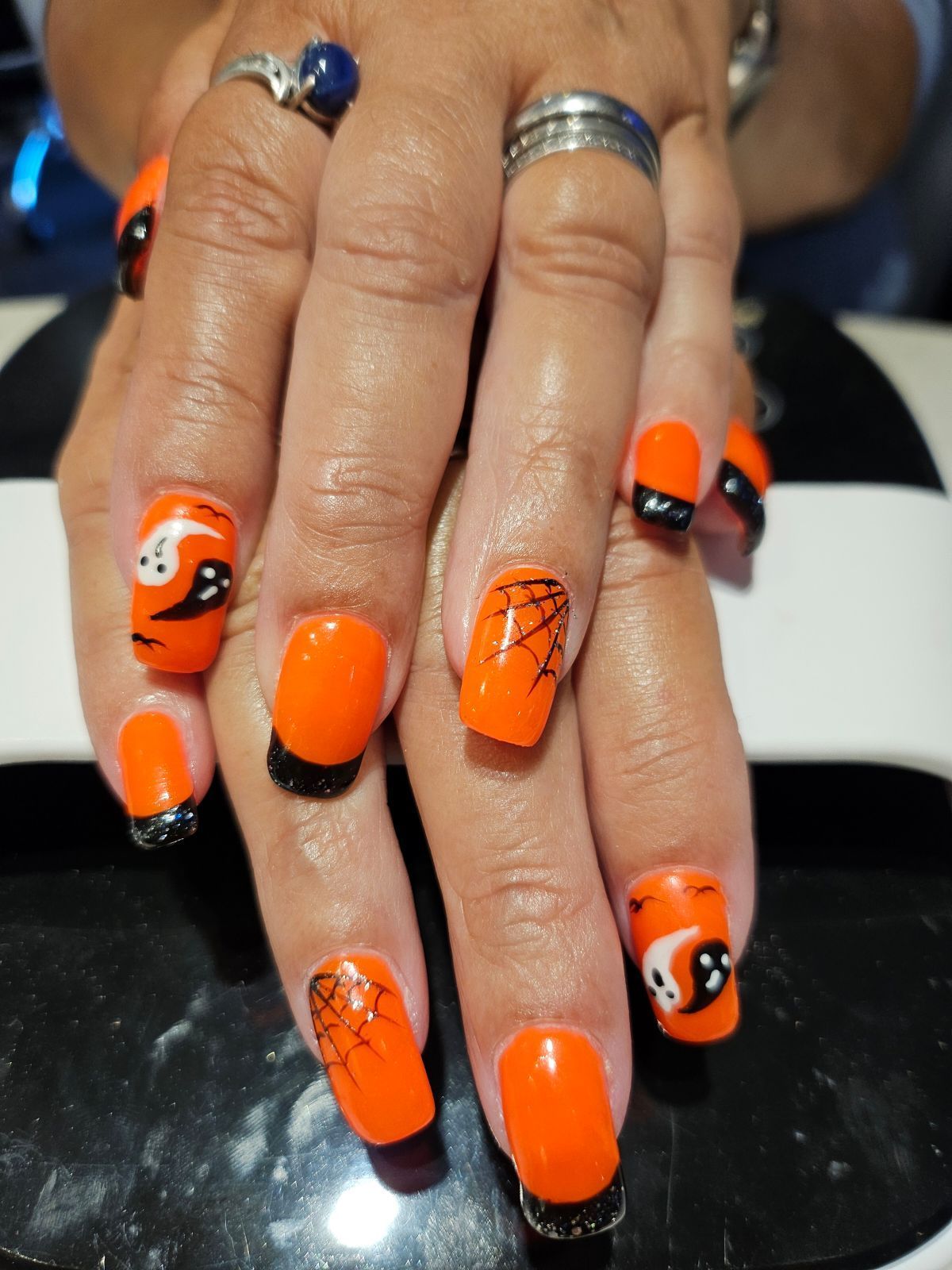Orange Halloween nail art with black accents, spiderwebs, and ghosts.
