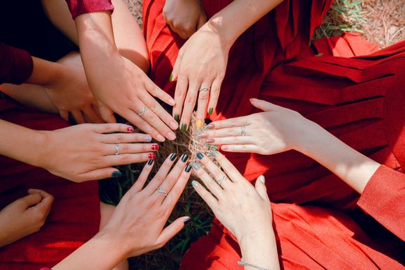 Hands holding an assortment of colorful nail polish bottles, with each nail painted a different shade.