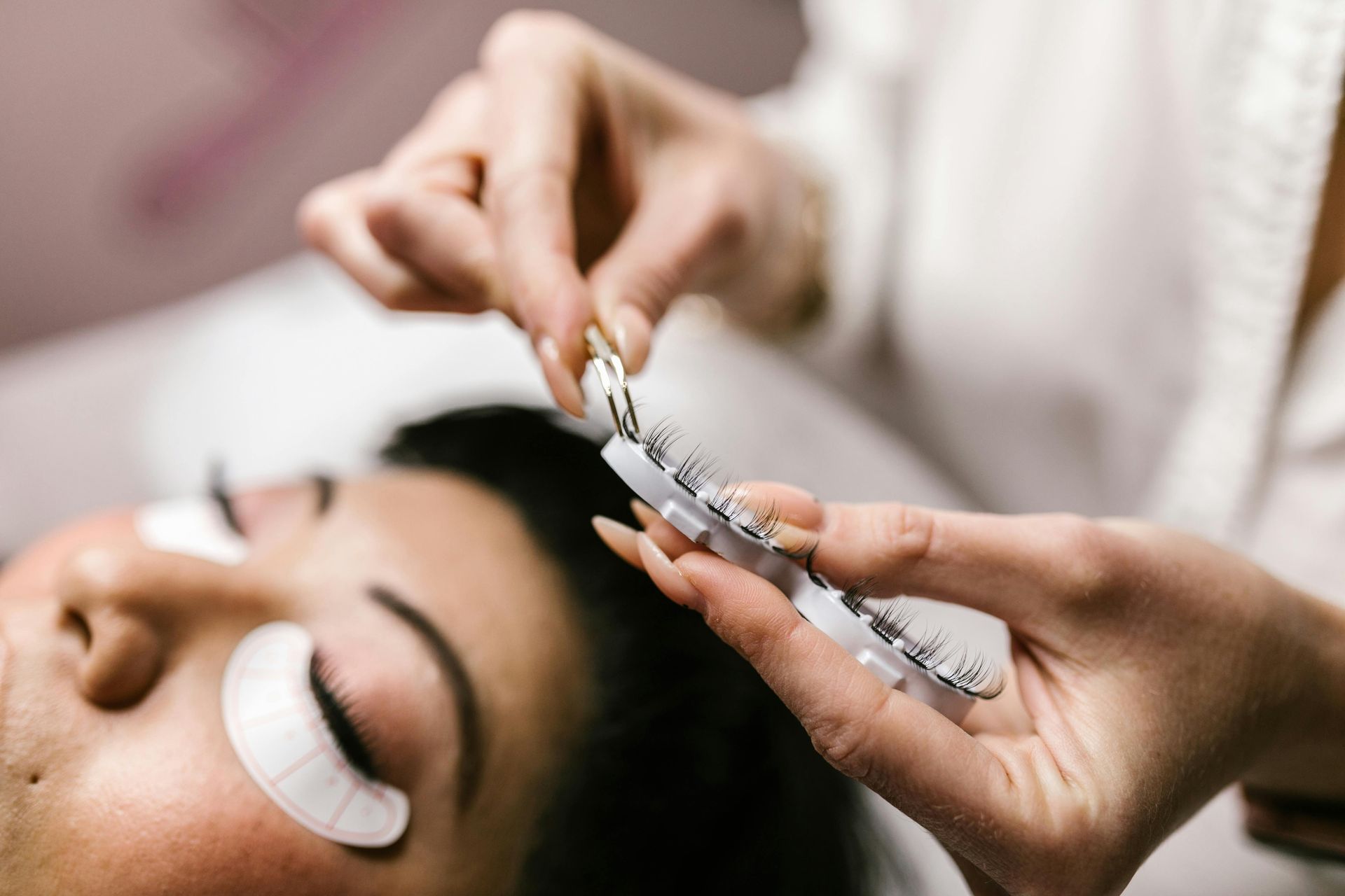 A person getting eyelash extensions applied by a technician; close-up.
