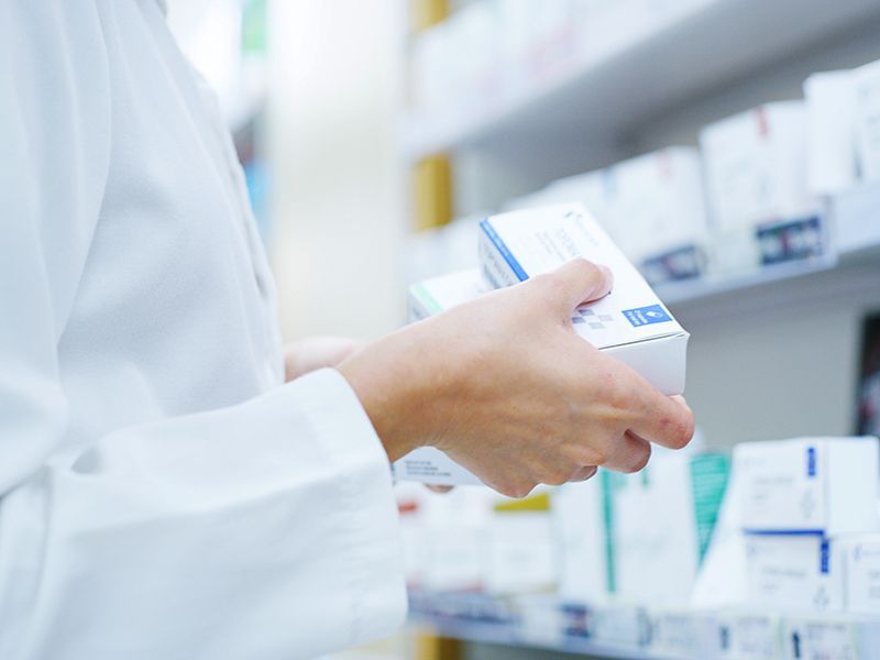 Un farmacista tiene in mano una scatola di pillole in una farmacia.