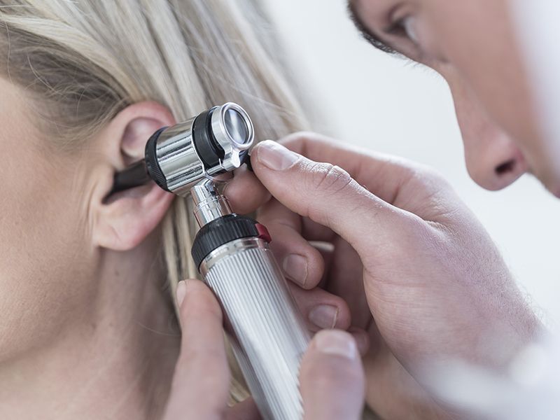 Un medico sta esaminando l'orecchio di una donna con uno stetoscopio.