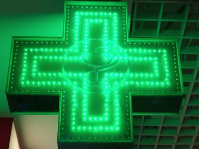 In una farmacia è accesa una croce luminosa verde.