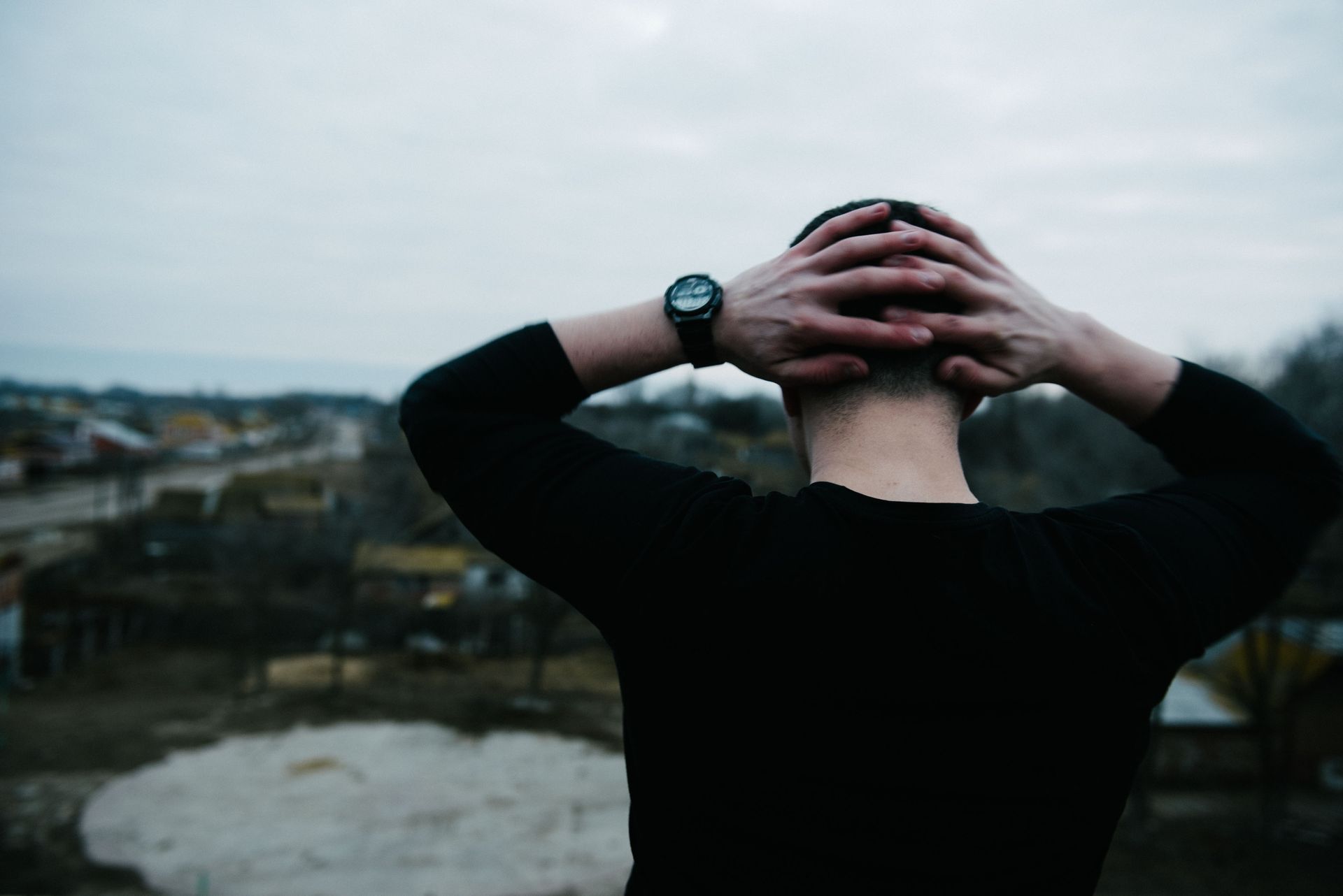 A man wearing a watch is holding his head in his hands.