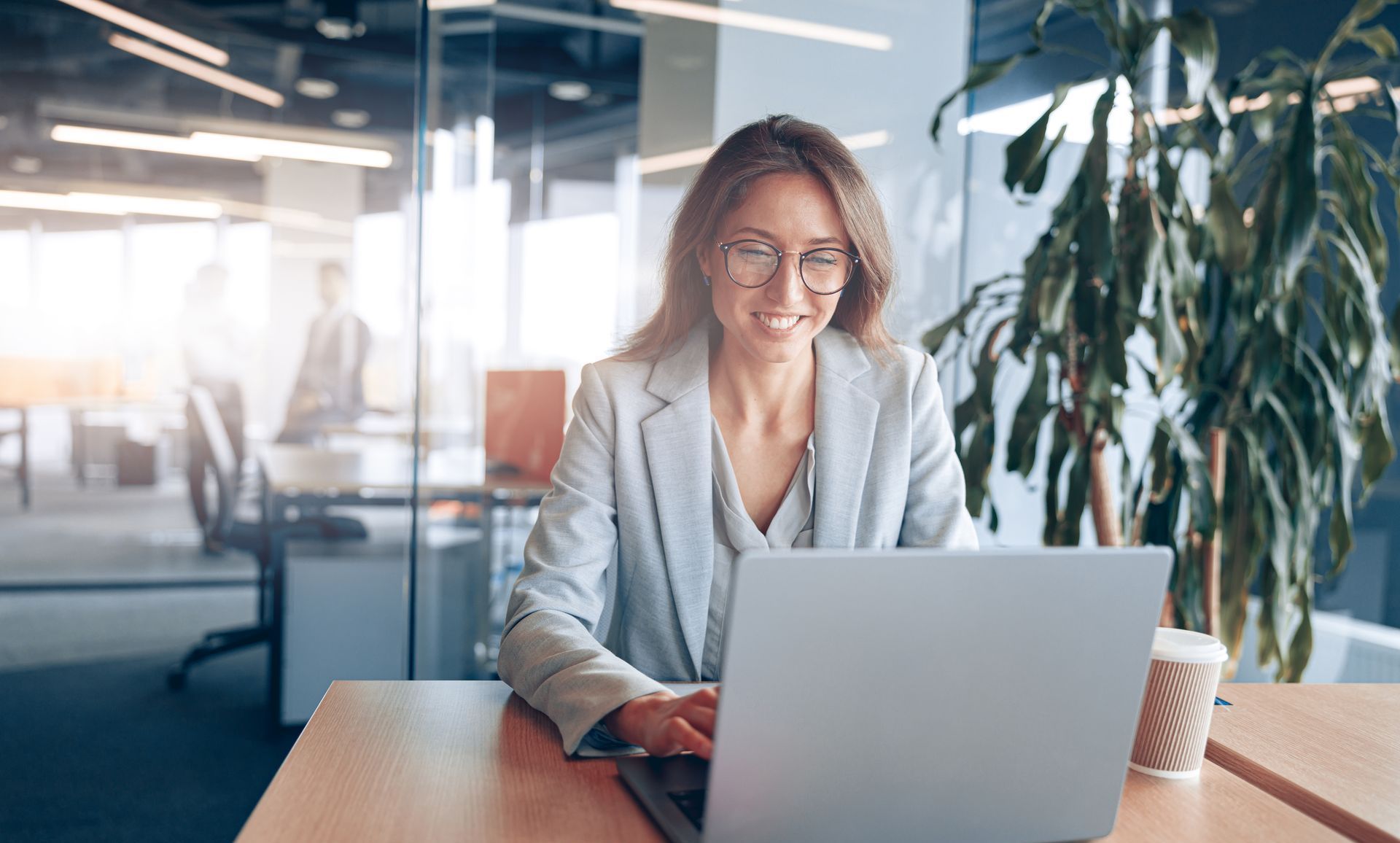 A woman is smiling in front of a group of people in an office.