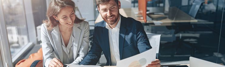 A man and a woman are sitting at a table looking at a piece of paper.