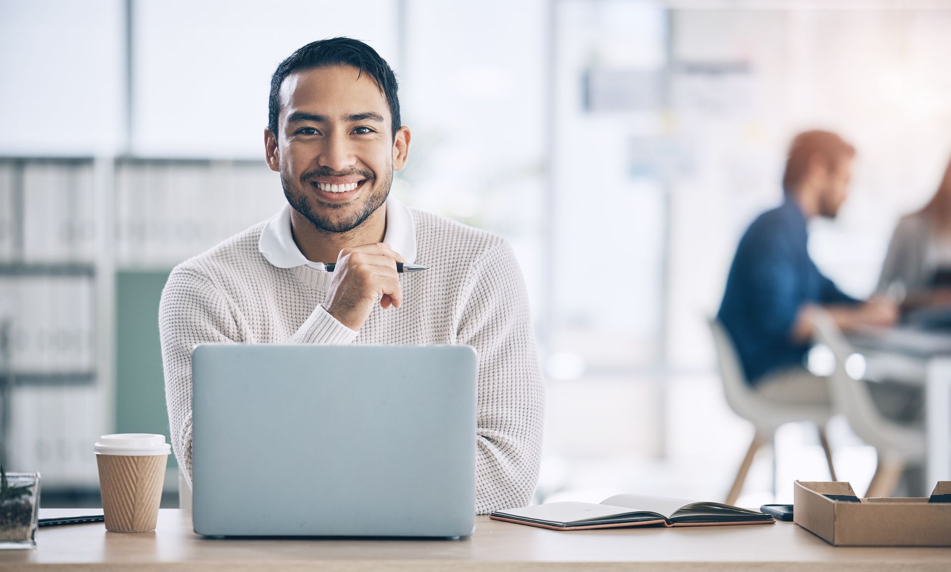 A man is sitting at a desk in front of a laptop computer.