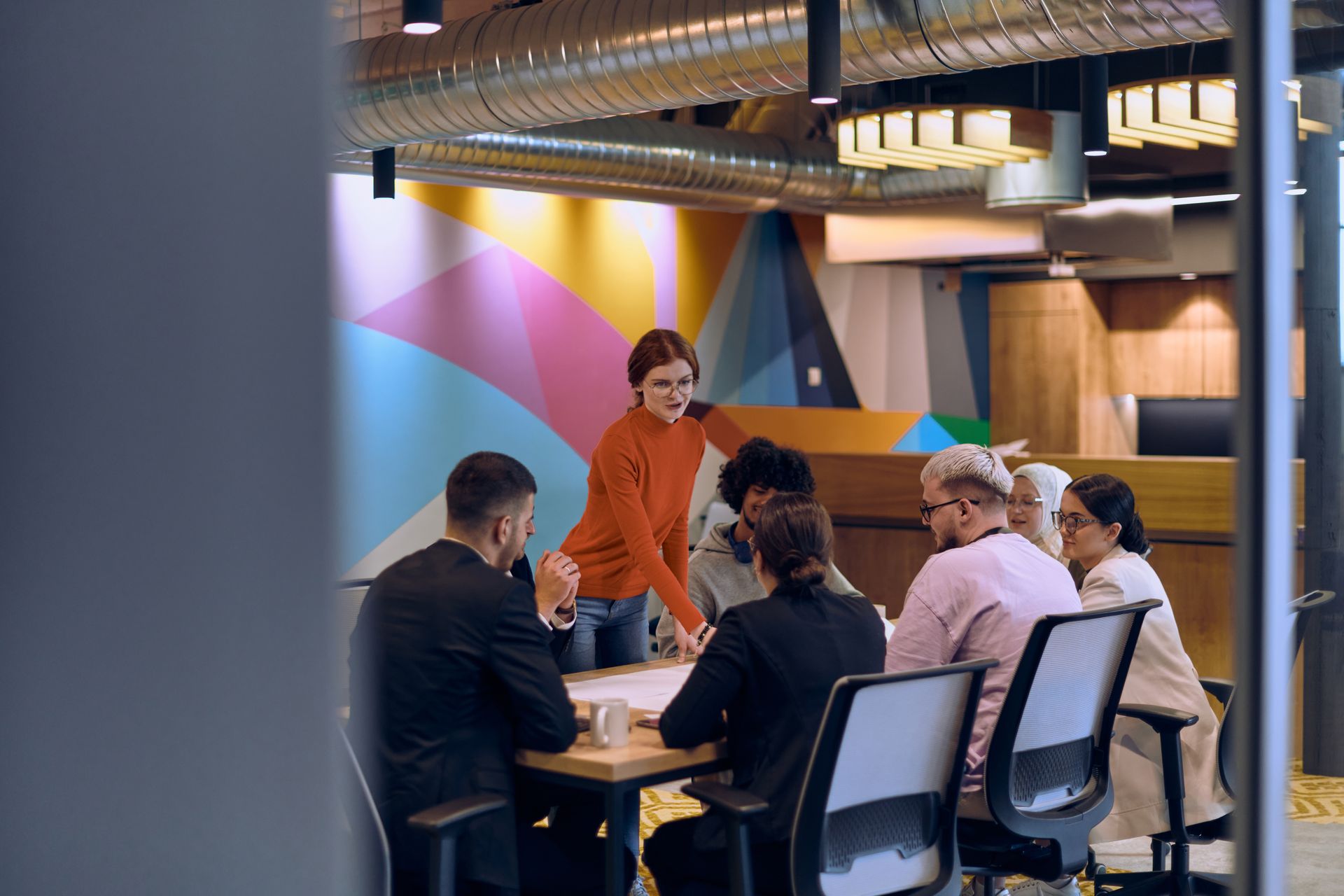 A group of people are sitting around a table having a meeting.