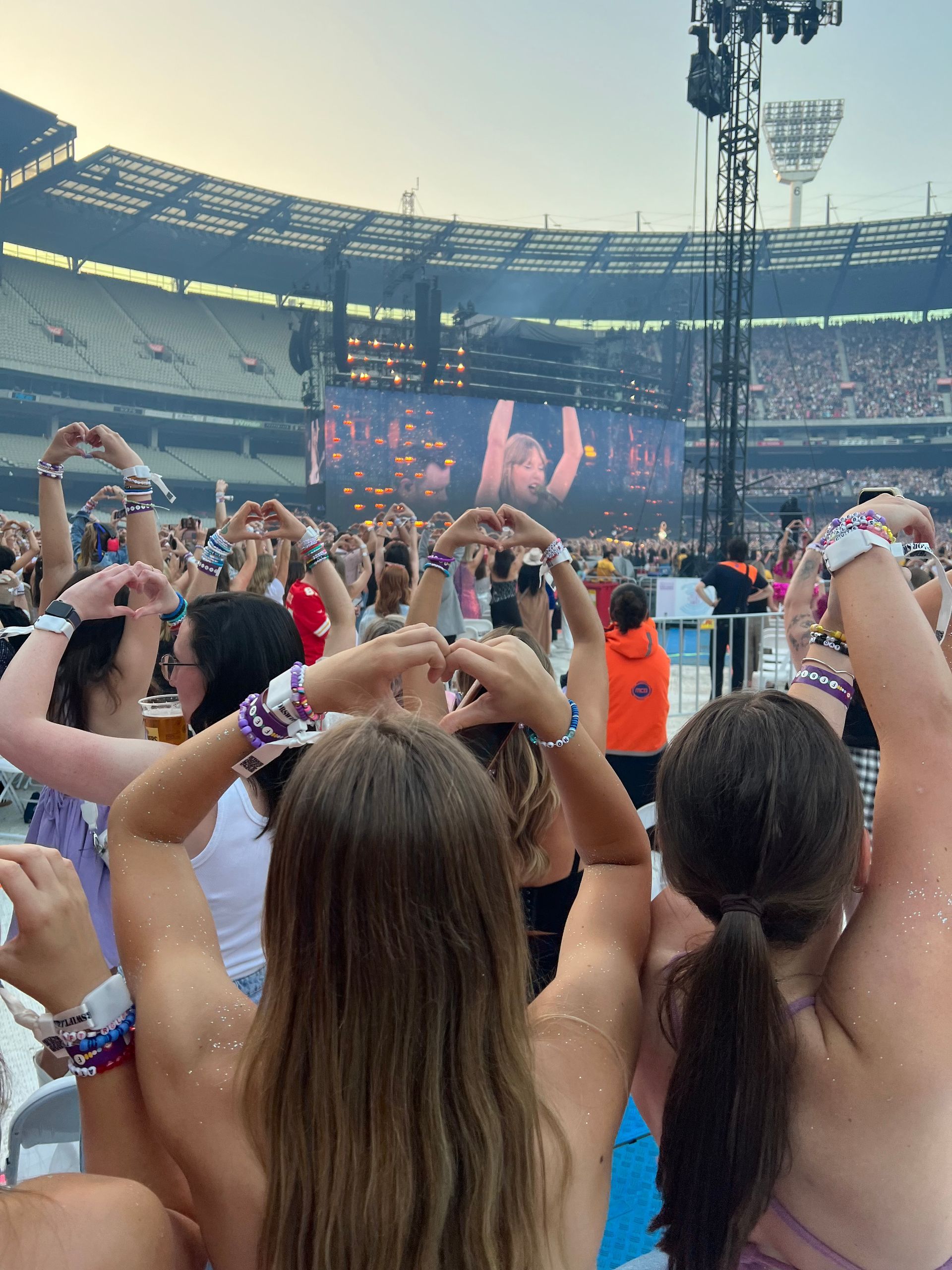 A group of people are sitting in a stadium with their arms in the air.
