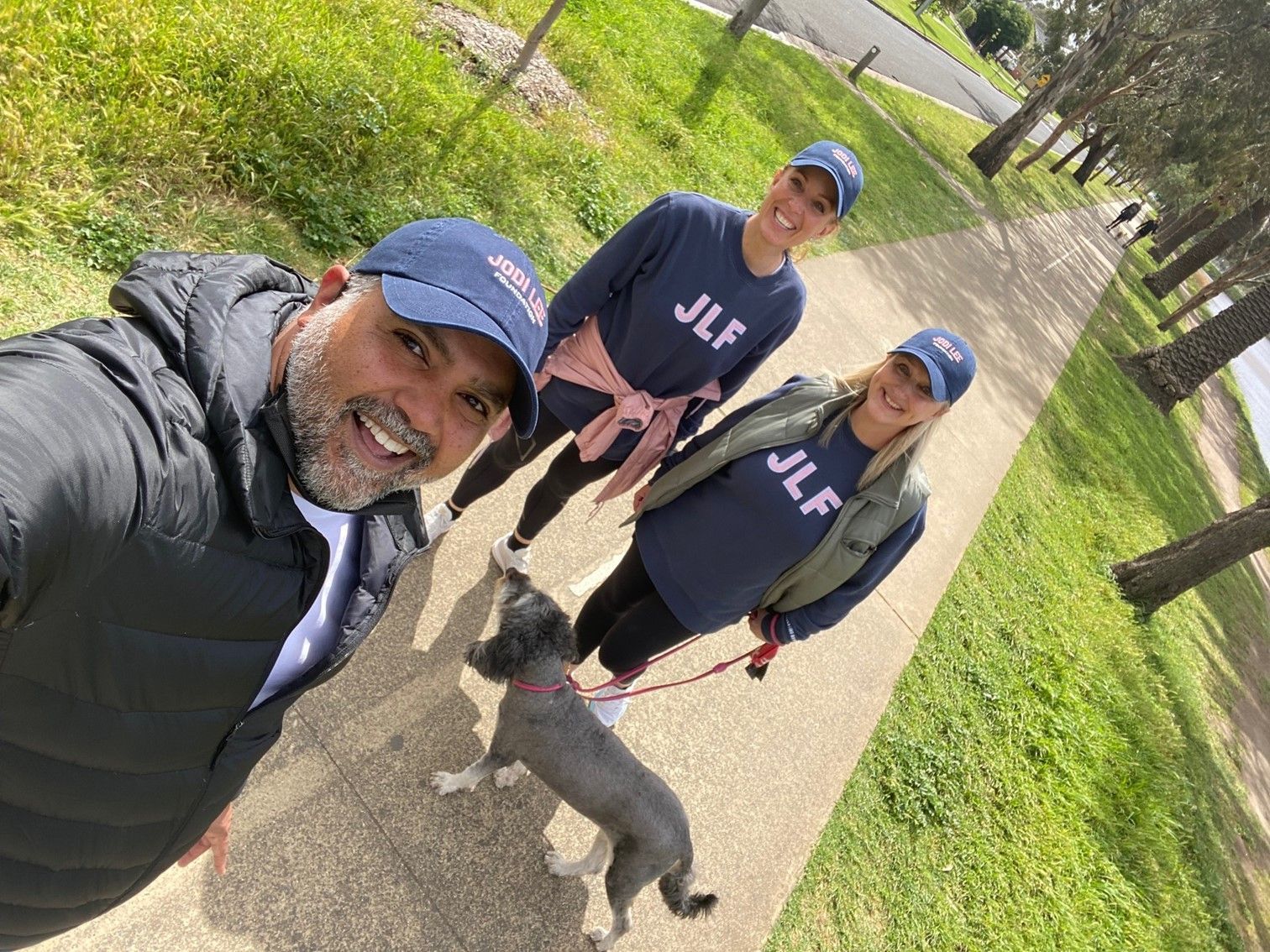 A man and two women are walking a dog on a leash.