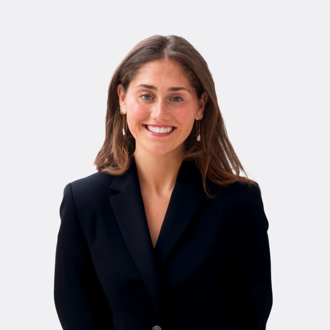 A woman wearing a white shirt and a pink belt is smiling for the camera.