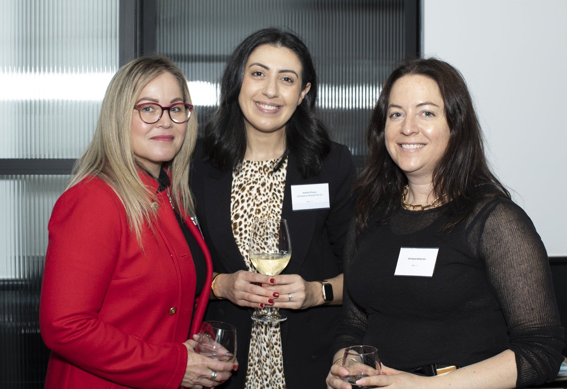 Three women are posing for a picture while holding wine glasses.