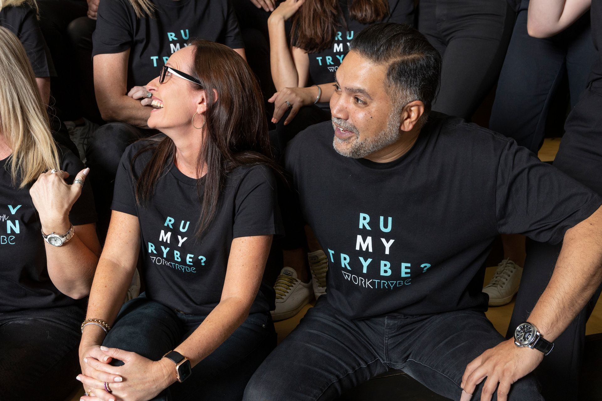 A man and a woman are sitting next to each other in a group of people.